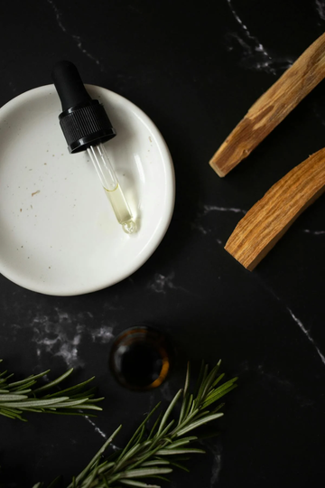 Image of a pipette of rosemary oil and rosemary water on a dark surface. Taken from Pexels