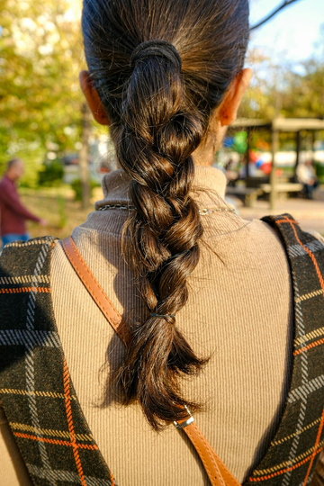 Image of a girl with a long thick braid from behind. Taken from Pexels