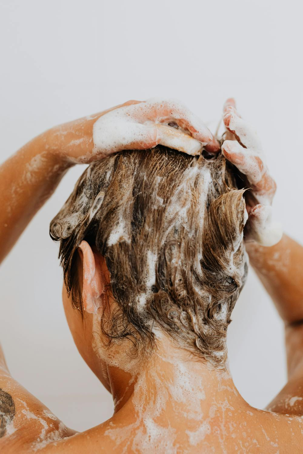 Image of a girl washing her hair in the shower. Taken from Pexels