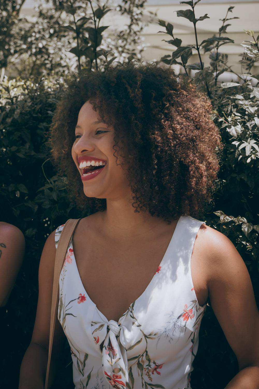 Image of a girl with curly hair smiling. Taken from Pexels