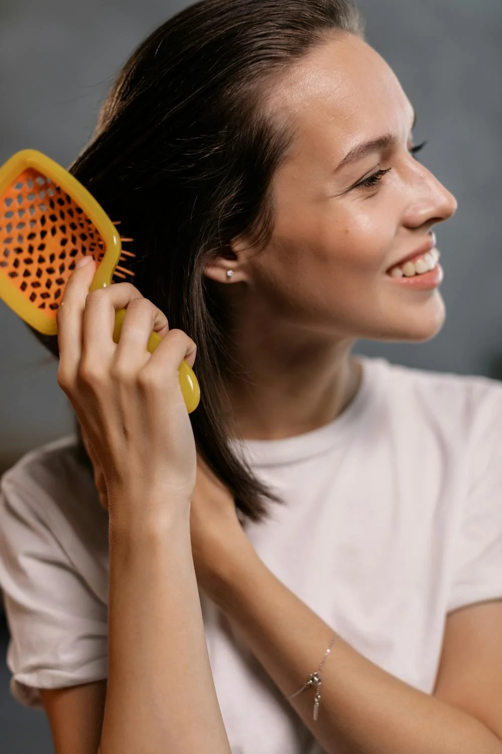 Image of a lady brushing her healthy hair with a hairbrush. Taken from Pexels