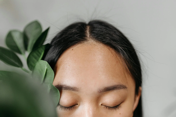 Image of a closeup of a girl's forehead, taken standing next to foliage. Taken from Pexels