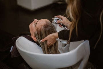 Image of a woman washing a client’s hair in a sink in a beauty salon.