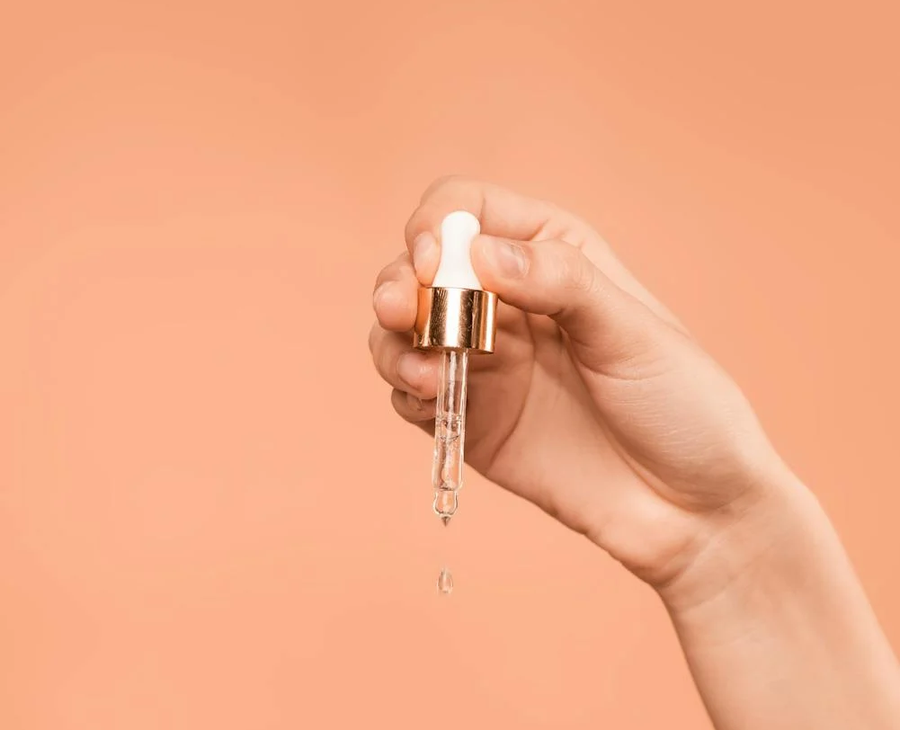 Image of a hand and a pipette of argan oil. 