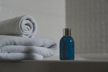 Image of a towel next to a bottle of shampoo. 