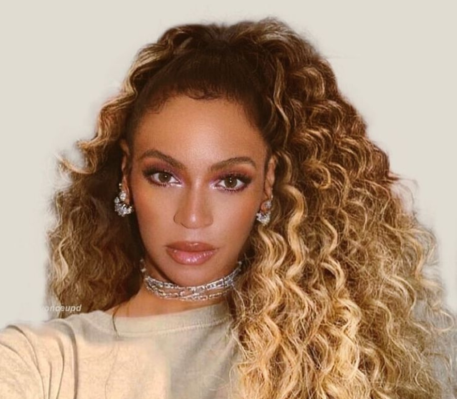 Beyoncé with a long, blonde, curly ponytail draped over her shoulder.