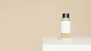 A minimalist image of a small, unlabeled bottle of oil on a white surface.