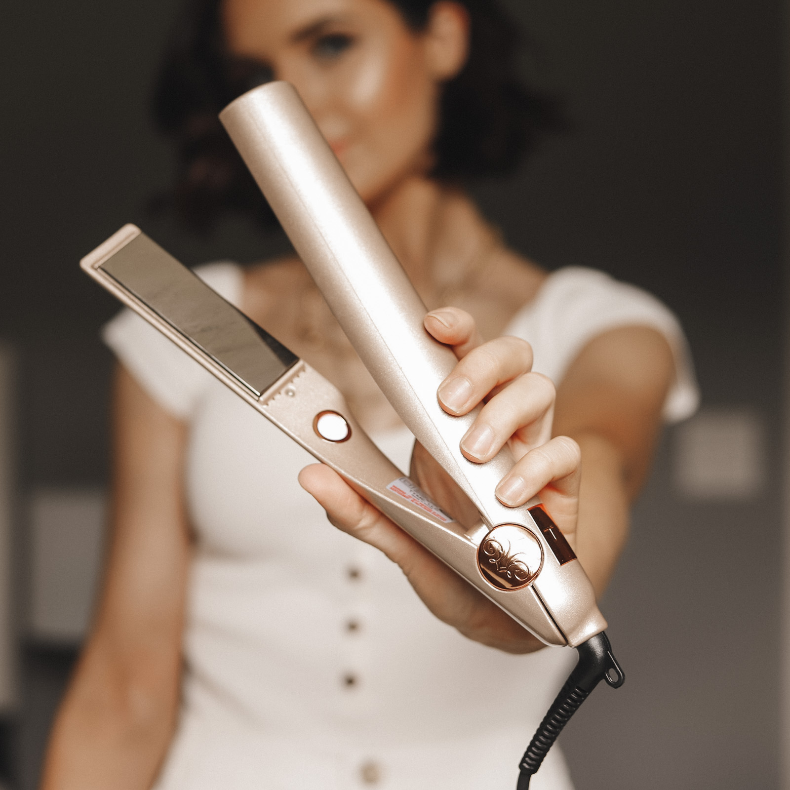 Woman in a white shirt holding a Tyme hair straightener curler